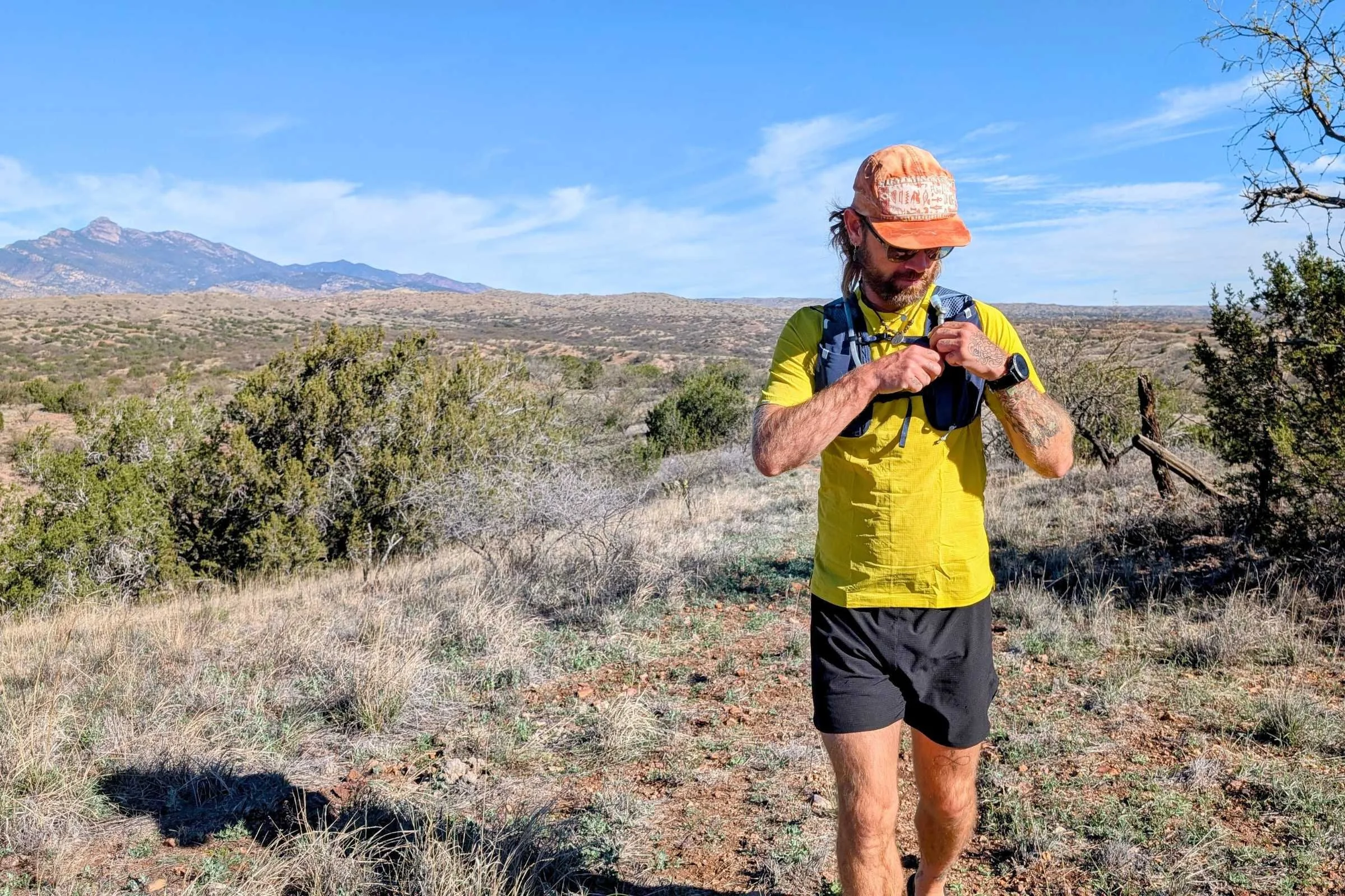 A runner wearing the REI Swiftland vest packed with gear on a trail