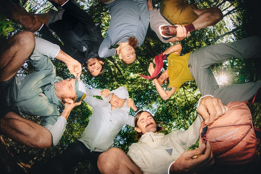 A group of people wearing Klättermusen SS26 collection standing in a rocky outdoor setting.
