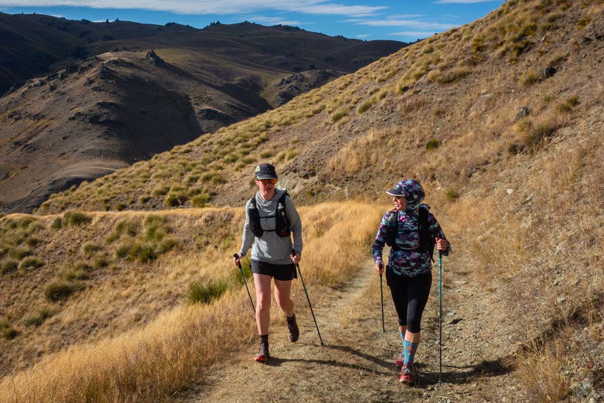 Two runners hiking and running through a scenic mountain trail during a fastpacking trip.