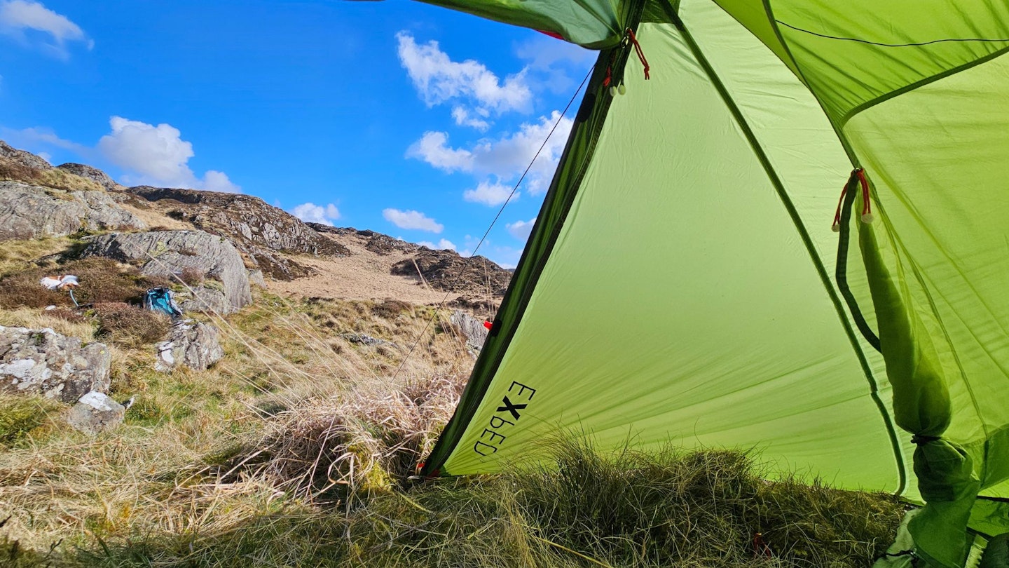 Detailed view of a tent porch and gear storage area in the wilderness.