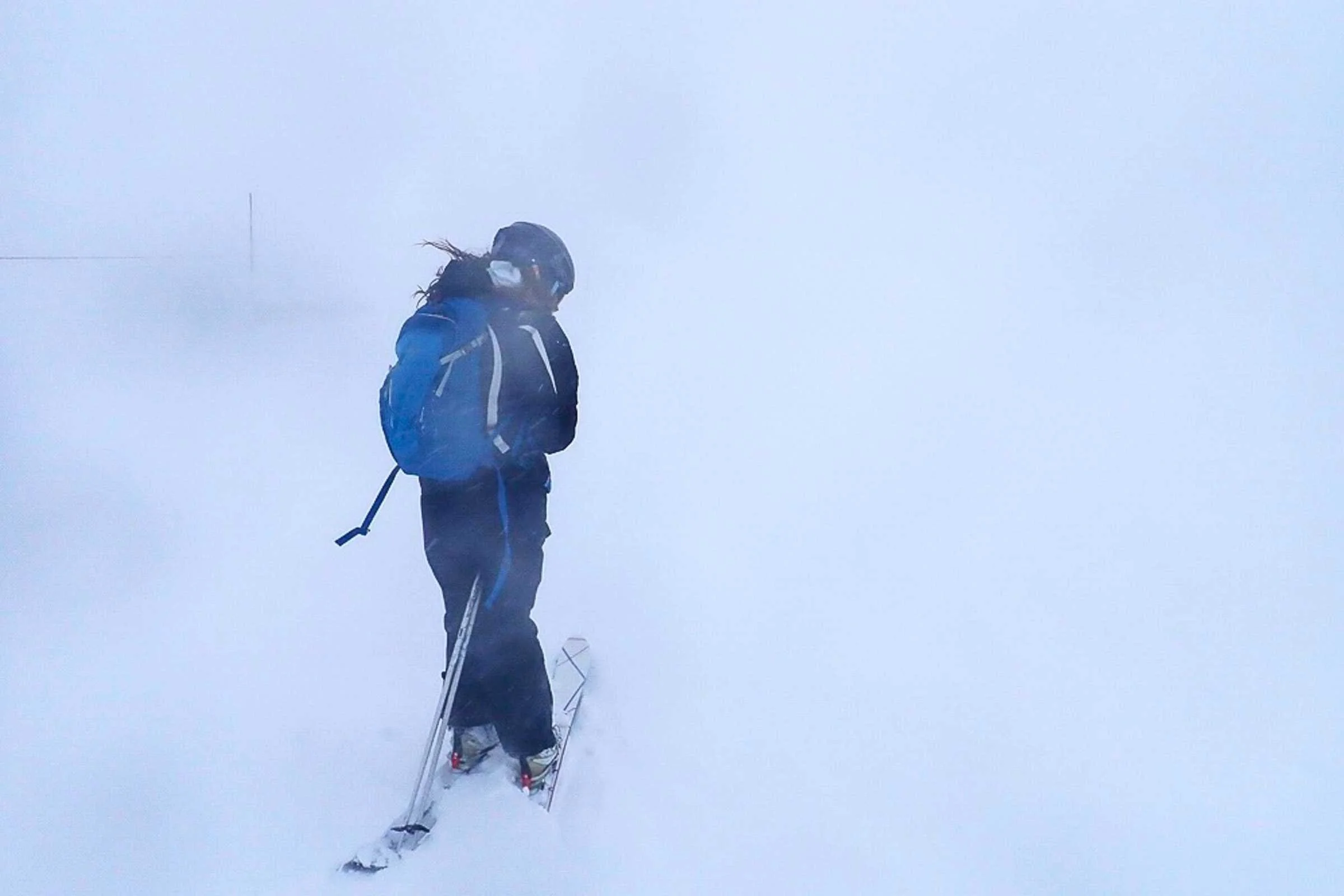 A skier using a rugged camera during a heavy snowstorm on a mountain trail.
