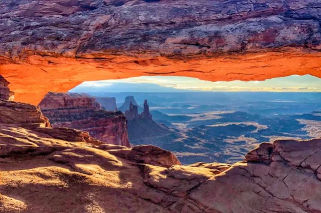 A natural stone arch framing a view of the layered mesas and canyons of Canyonlands.