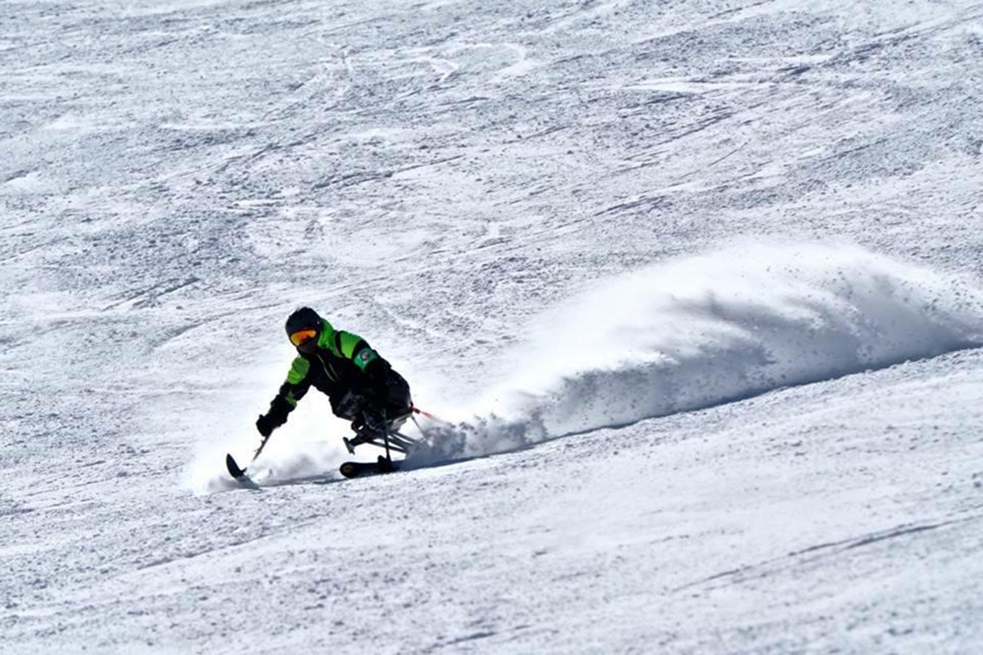 Hari Budha Magar using a sit-ski on a snowy slope.