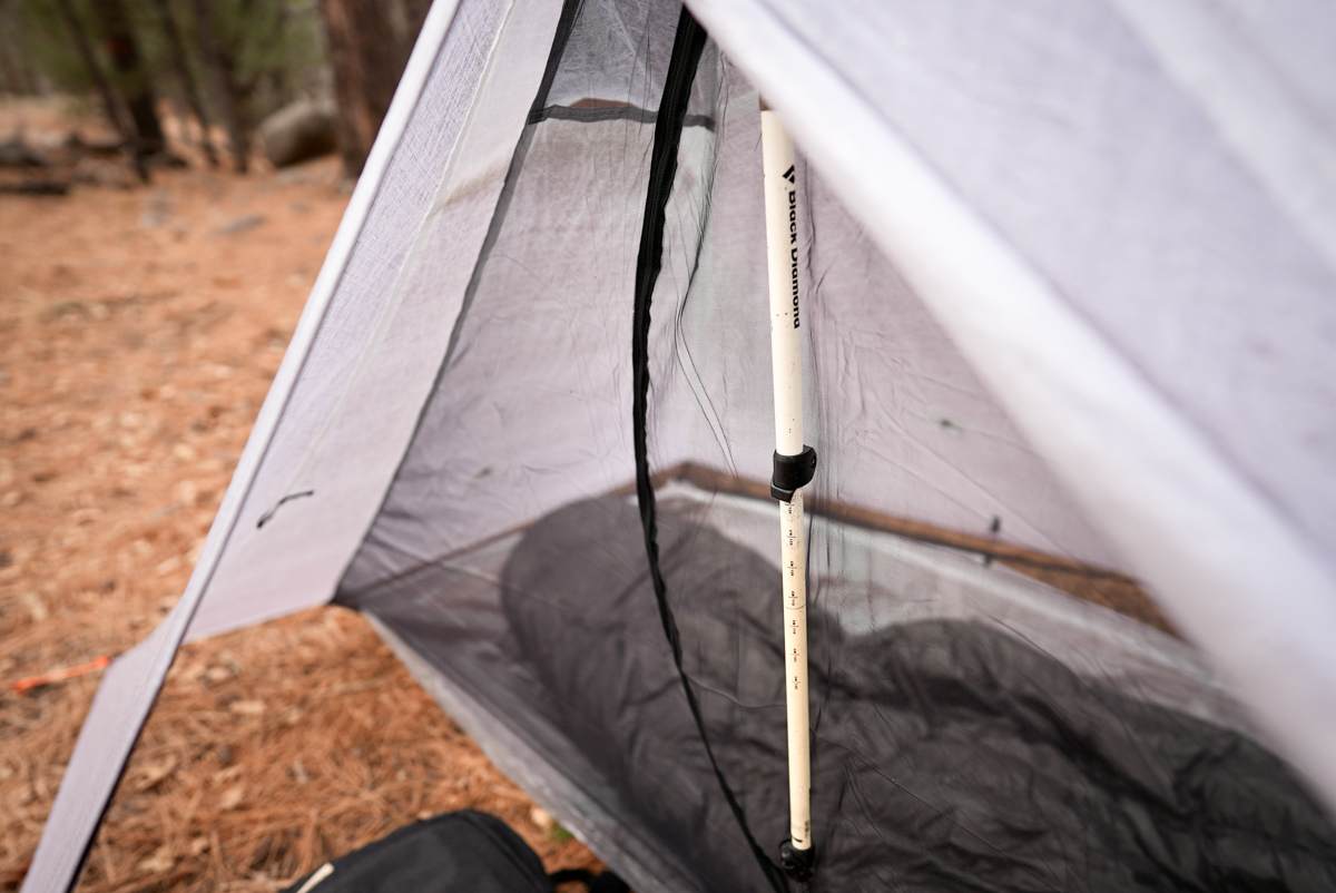 Close-up of a trekking pole handle supporting the peak of a lightweight tent.