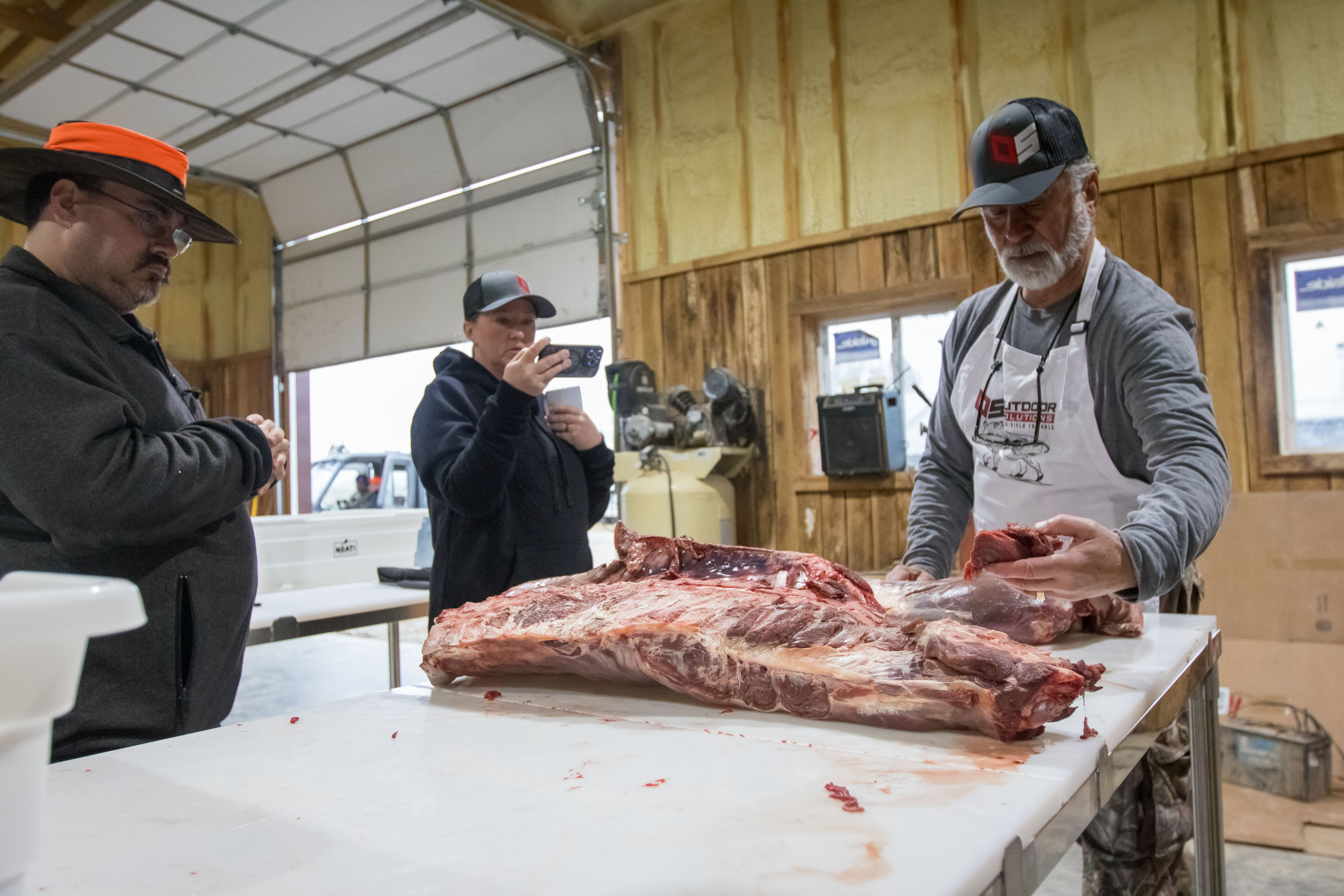 A professional chef demonstrating precise seam butchery techniques to a group of students.