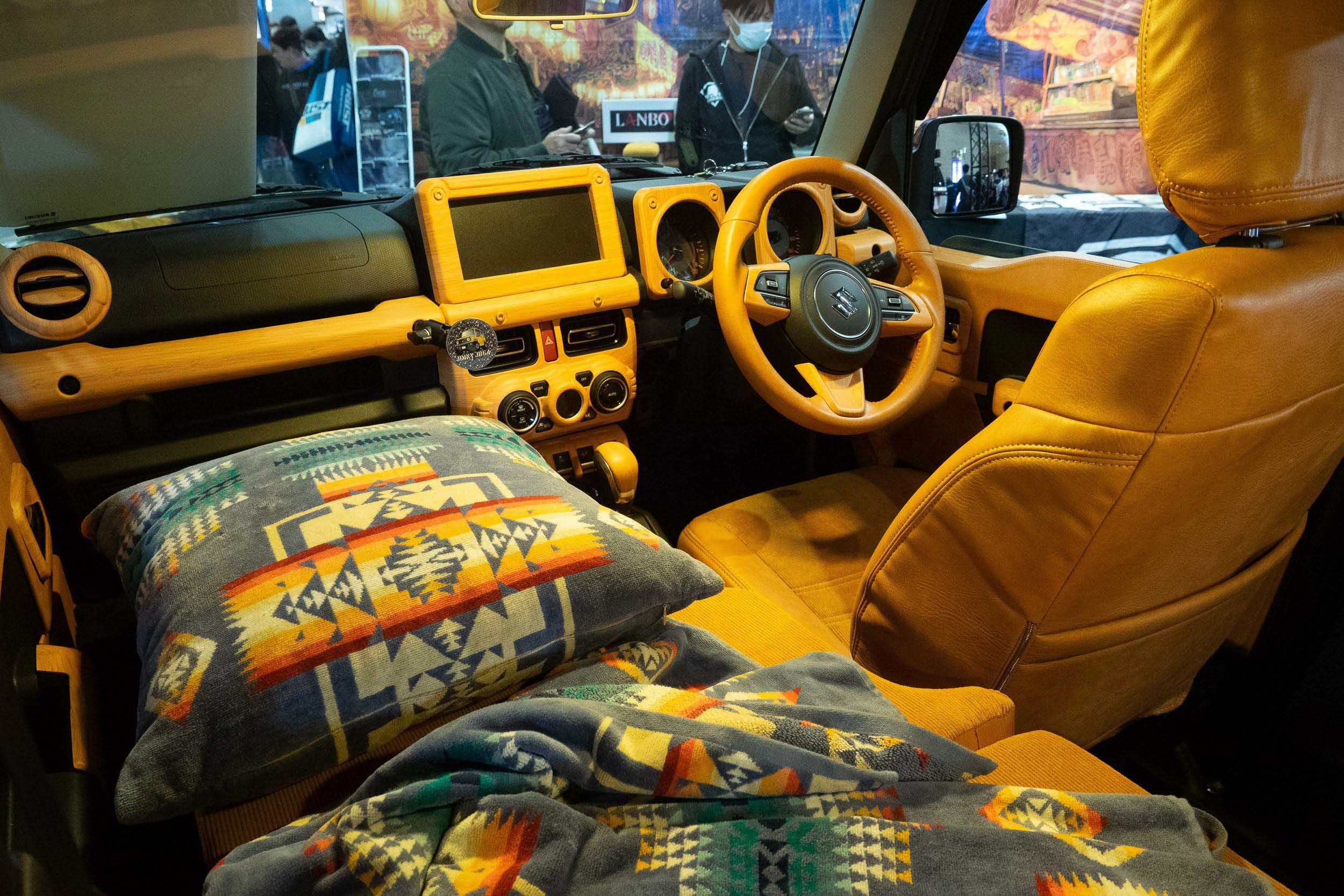 Interior view of a Suzuki Nomade micro-camper showing optimized storage and bedding.
