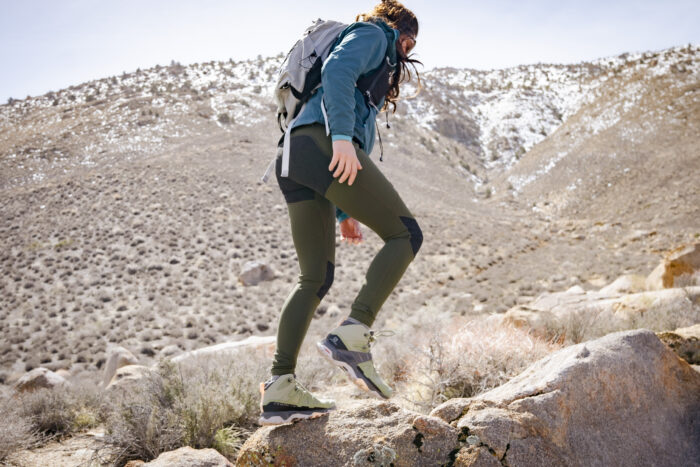 A female hiker from the side wearing a well-fitted technical daypack.