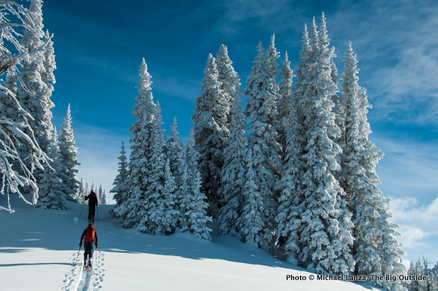 Skiers traversing a snowy ridge in the Teton Range.