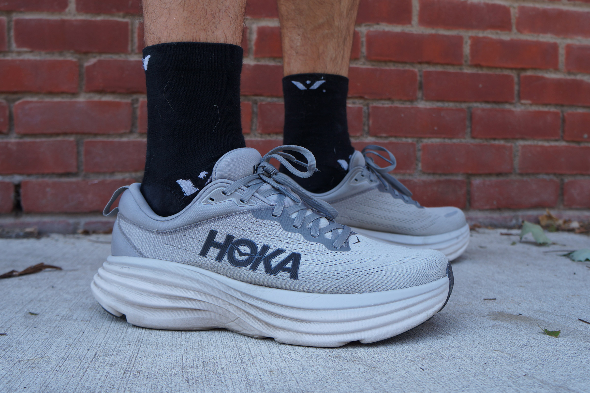A runner wearing grey Hoka Bondi maximalist cushion shoes.