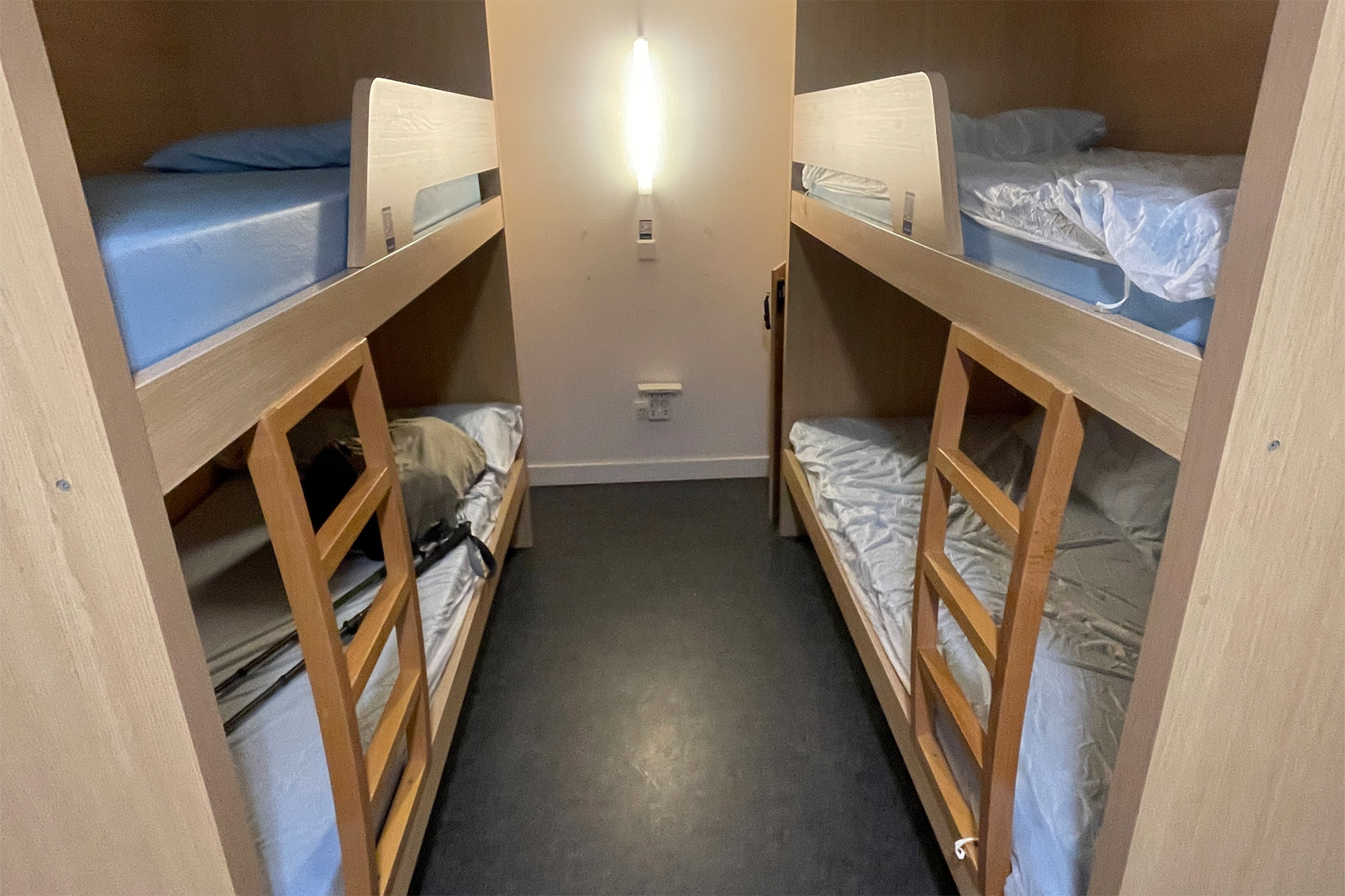 A room filled with wooden bunk beds in a simple, clean pilgrim hostel.
