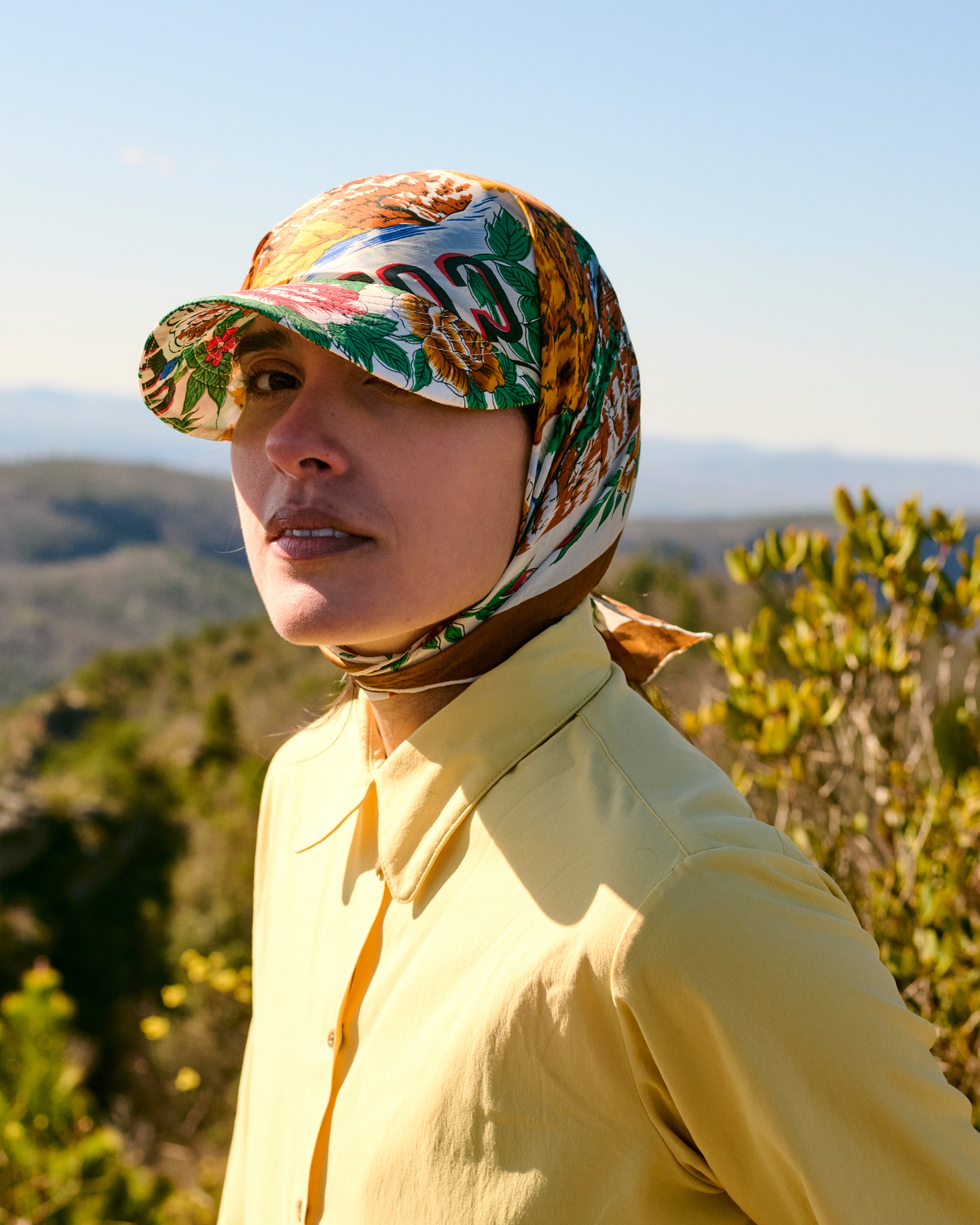 Various outdoor accessories including a hat and small gear pouches laid out on a rock.