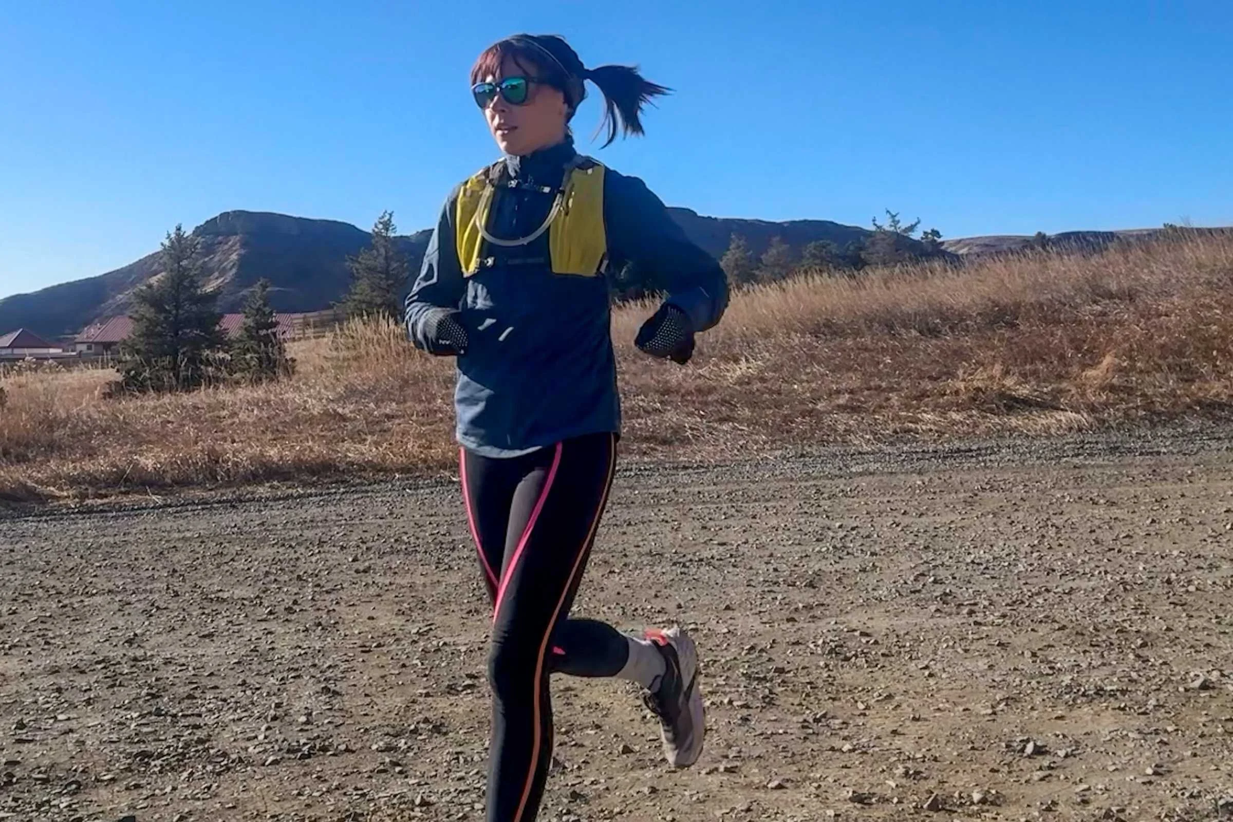 A woman wearing the REI Swiftland hydration vest while running in the Colorado mountains