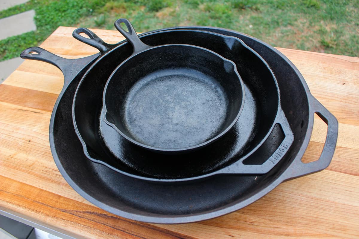 A stack of multiple clean and seasoned cast iron skillets showing their textured surface.