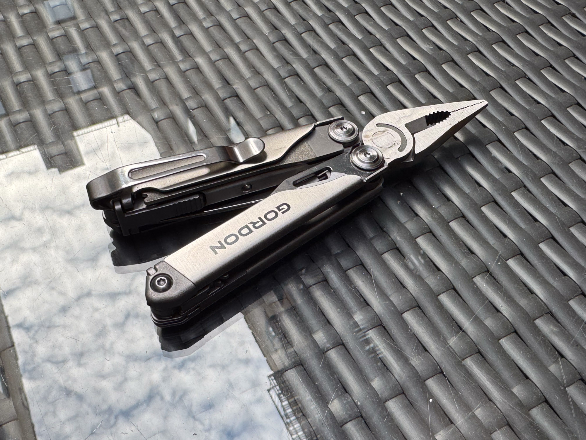 Gordon multi-tool resting on a glass table in an outdoor setting.