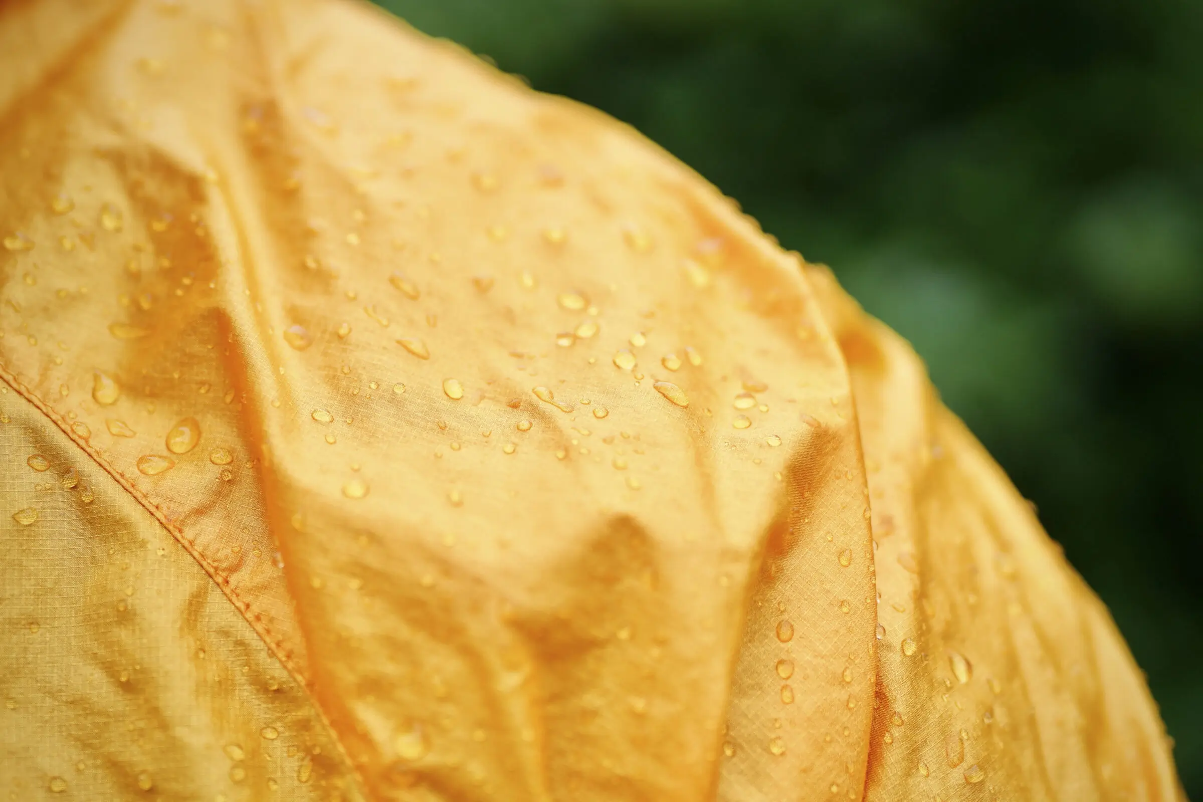 Macro shot of water droplets beading up on a technical windbreaker fabric.