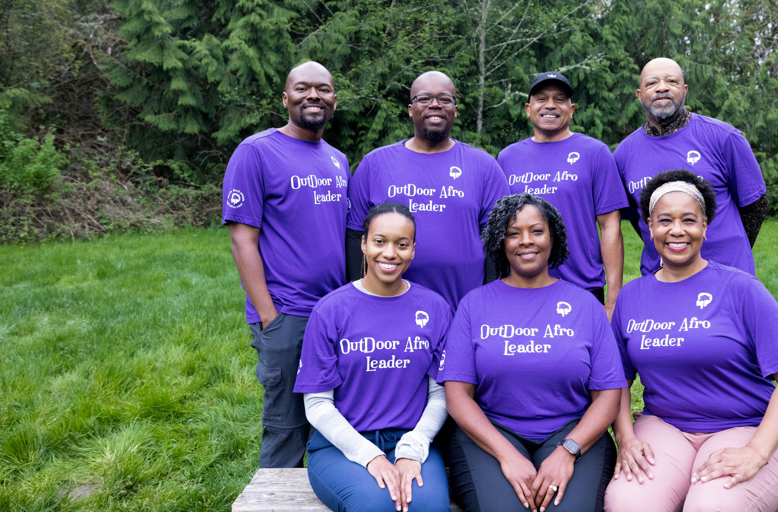An Outdoor Afro volunteer leader smiling in a sun-dappled forest setting.