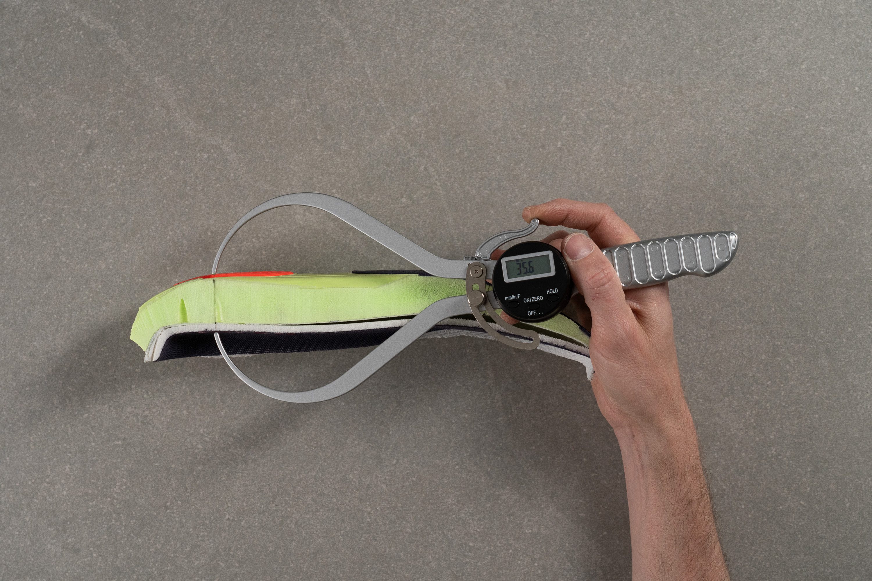 A digital caliper measuring the heel stack height of the HOKA Mach 7 midsole.